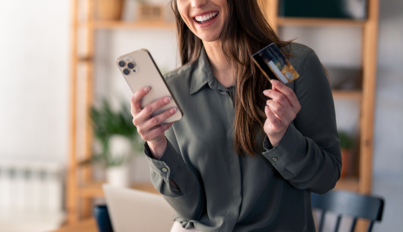 Young woman smiling and holding a smartphone and credit card, representing smart retail and omnichannel marketing